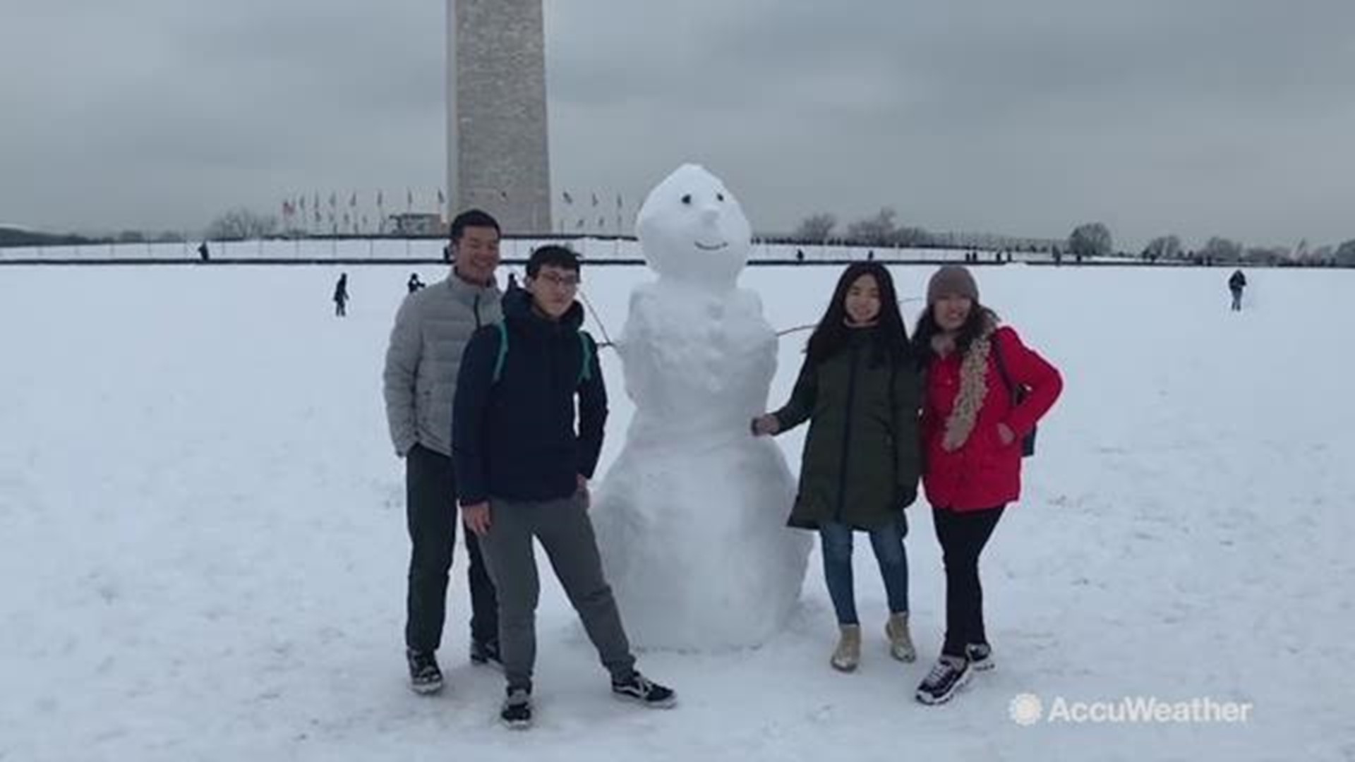 A group of people having a blast during the winter storm decides to pose for a picture with this snowman in Washington, DC on Jan. 13.