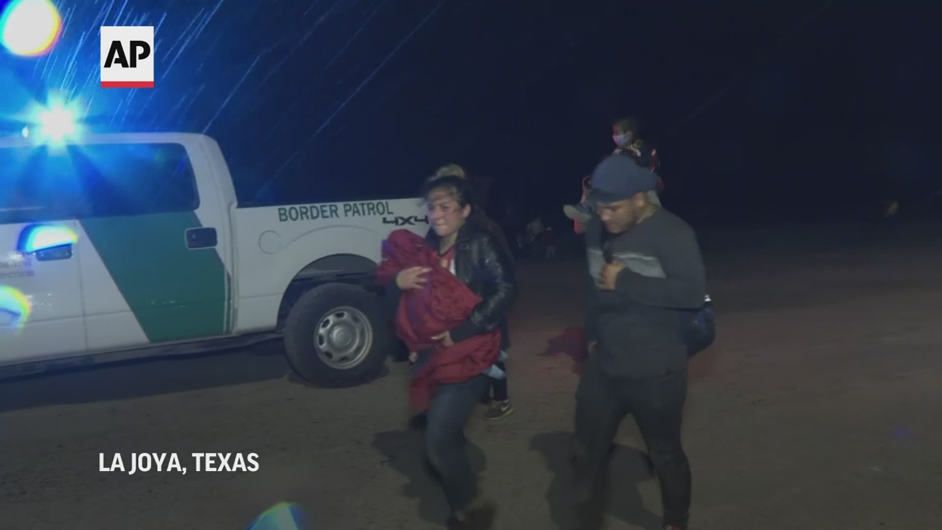 Parents emerge from the brush and driving rainstorms to a baseball field, carrying exhausted children in their arms.