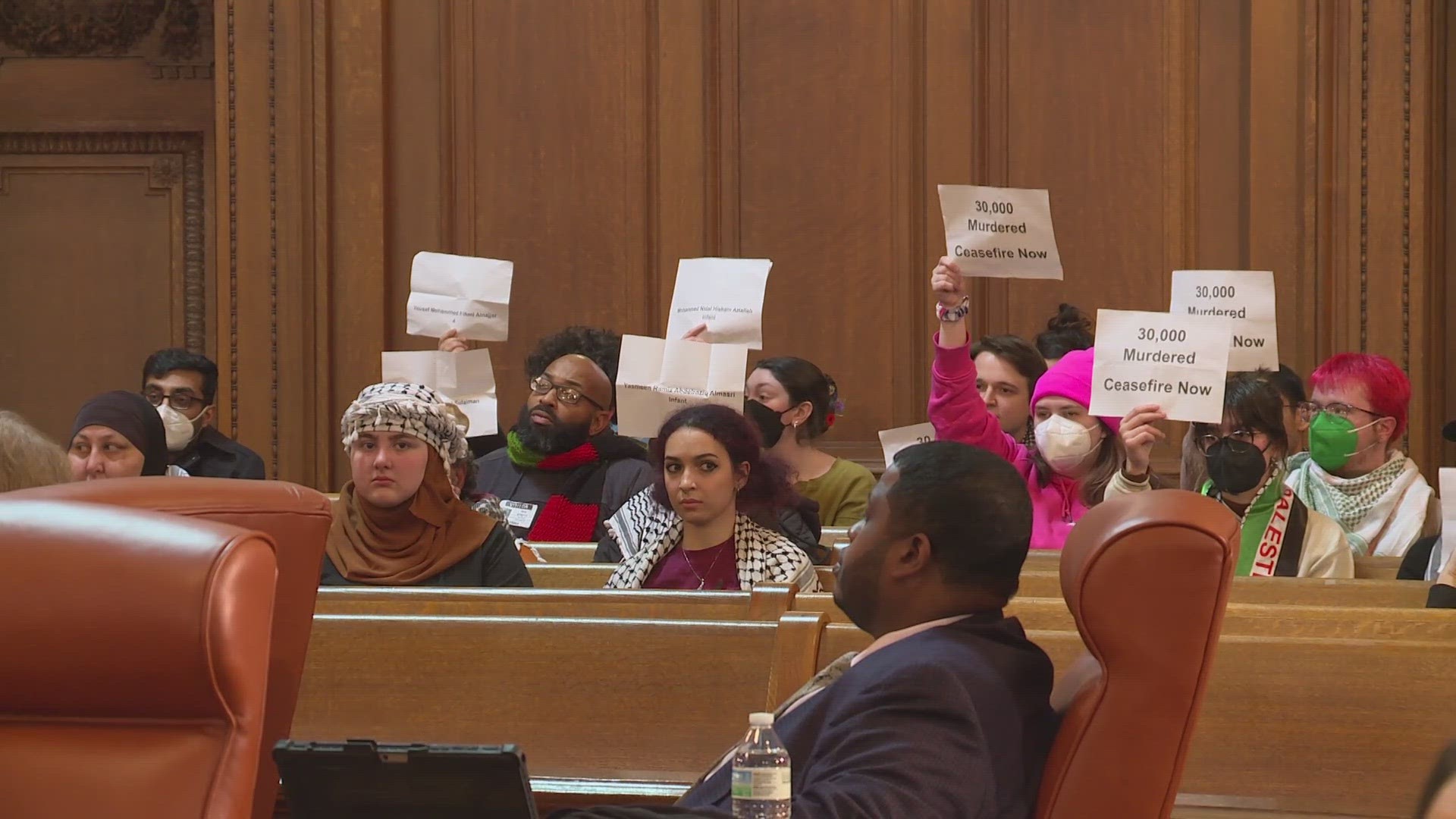 Pro-Palestine protestors could be heard chanting as the clerk read ordinances and resolutions off the agenda.